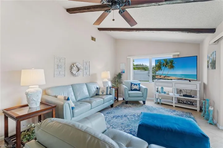 Tiled living area with ceiling fan, a textured ceiling, and baseboards