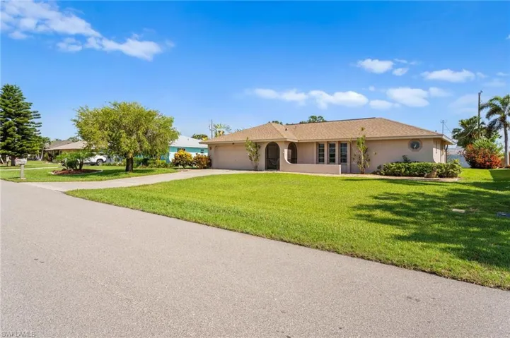 Ranch-style house with a garage, concrete driveway, a front lawn, and stucco siding