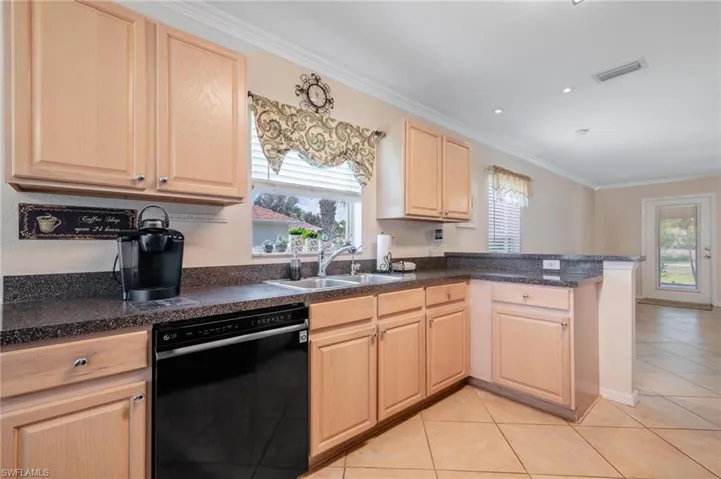 Kitchen with light tile floors, sink, plenty of natural light, and black appliances