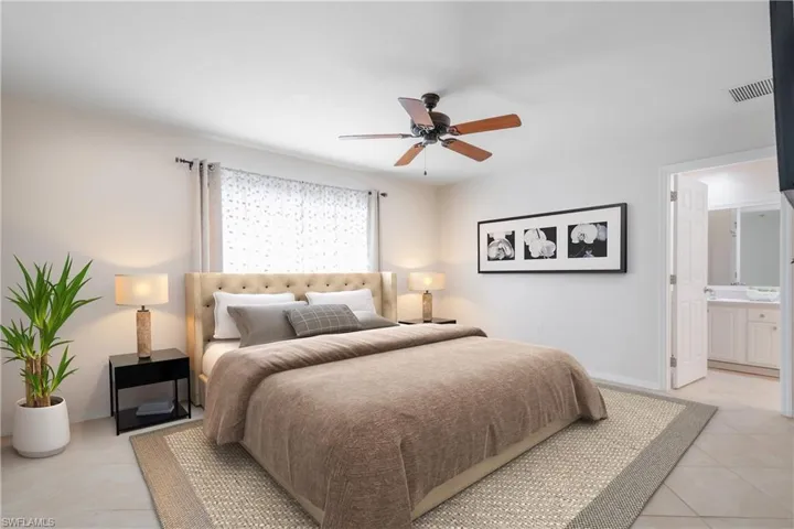 *Virtually staged-Primary tiled bedroom with ceiling fan, connected bathroom, and ornamental molding