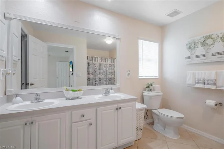 Primary Bathroom featuring dual vanity, tile flooring, and toilet