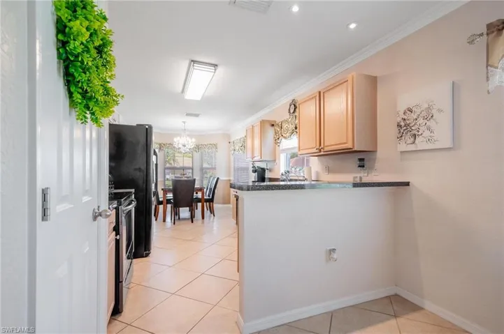 Kitchen featuring decorative light fixtures, neutral tile flooring, and black appliances