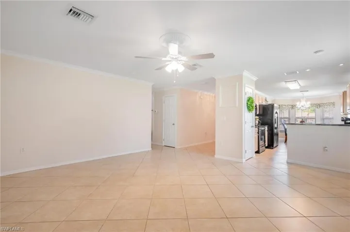Great room featuring neutral tile, crown molding and ceiling fan