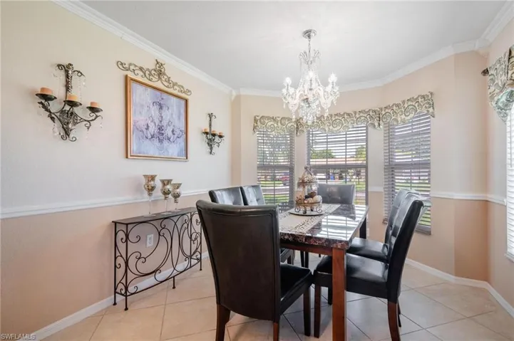 Tiled dining area with an inviting chandelier and crown molding
