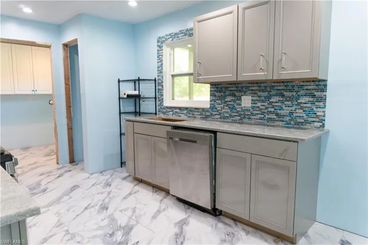 Kitchen with dishwasher, tasteful backsplash, and gray cabinetry