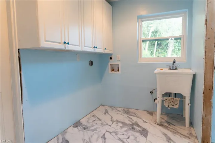 Washroom with electric dryer hookup, cabinets, and hookup for a washing machine