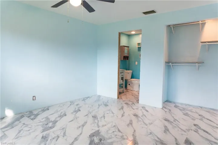 Unfurnished bedroom featuring connected bathroom, a closet, and ceiling fan
