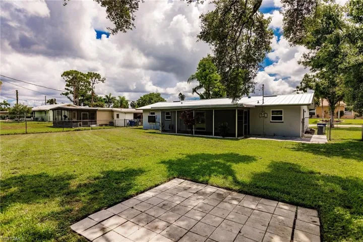Rear view of property featuring a lawn, a patio, and a sunroom