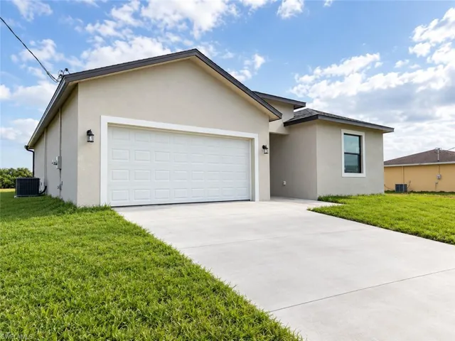 Stucco exterior with a two-car garage, concrete driveway, and exterior wall sconces