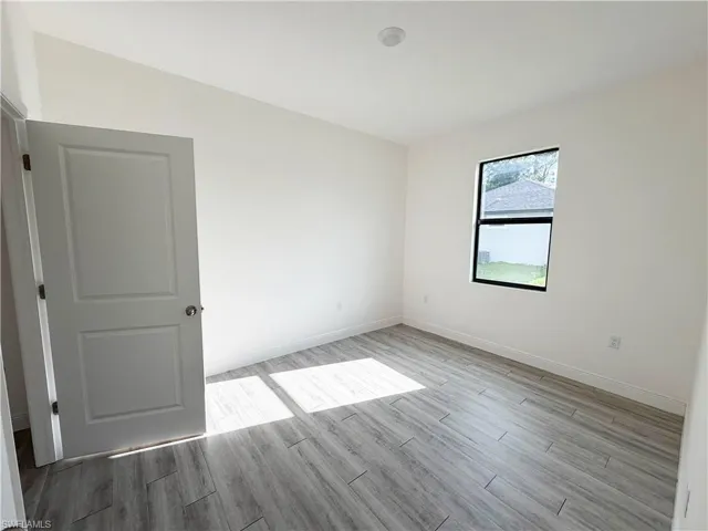 Light-toned wood-finish flooring, white walls, modern trim, and a contemporary window frame