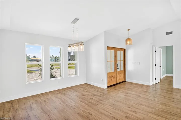 Unfurnished room with lofted ceiling, light wood finished floors, and a chandelier