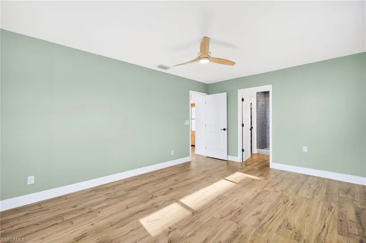 Unfurnished bedroom featuring light wood-type flooring, a ceiling fan, and ensuite bathroom