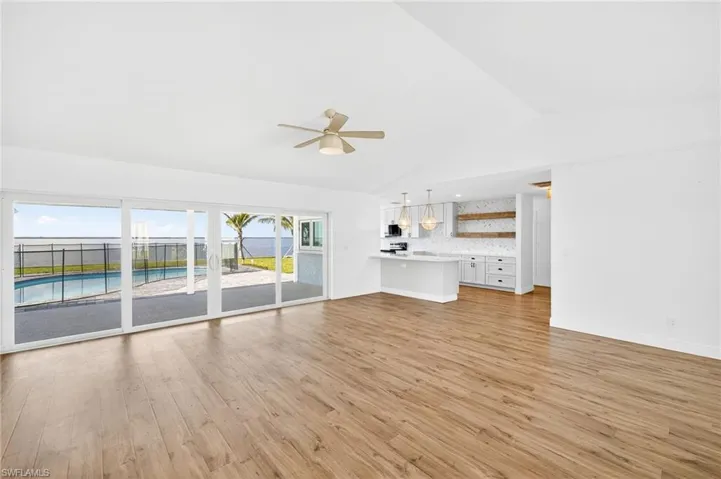 Unfurnished living room with light wood finished floors, lofted ceiling, ceiling fan, and a water view