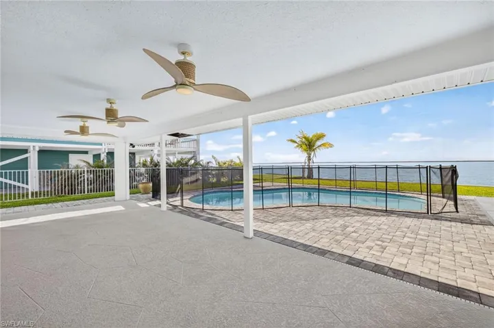 View of swimming pool with a patio area, a ceiling fan, and a water view