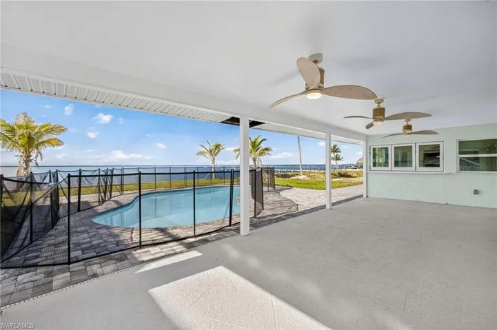 View of swimming pool featuring a patio area, a ceiling fan, and a water view