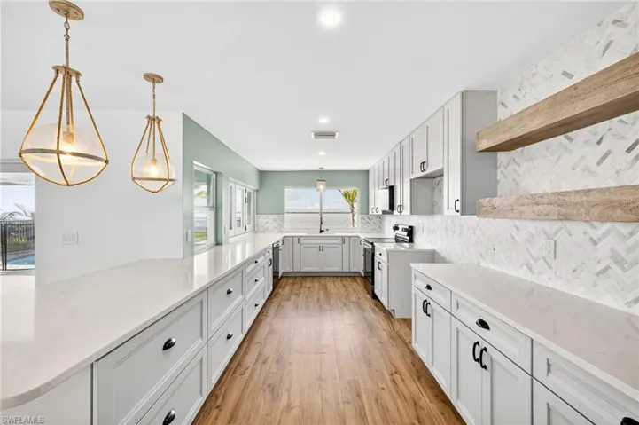 Kitchen with open shelves, light wood-style floors, stainless steel electric range, backsplash, and pendant lighting