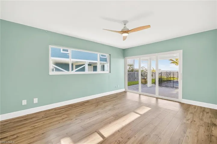 Empty room featuring healthy amount of natural light, wood finished floors, and ceiling fan