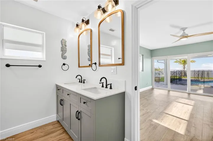 Full bath with wood finished floors, double vanity, and a ceiling fan
