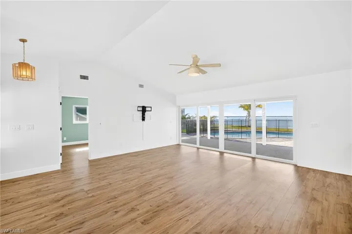 Unfurnished living room featuring ceiling fan, wood finished floors, and lofted ceiling