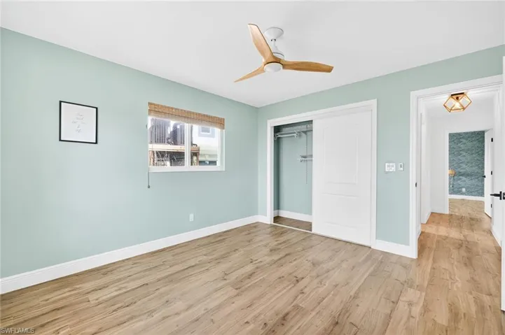 Unfurnished bedroom featuring light wood-style floors, a closet, and ceiling fan
