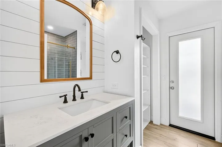 Full bath with vanity, wood finished floors, and a shower