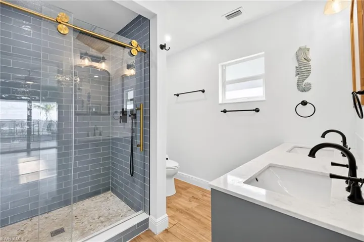 Bathroom with a stall shower, wood finished floors, and double vanity