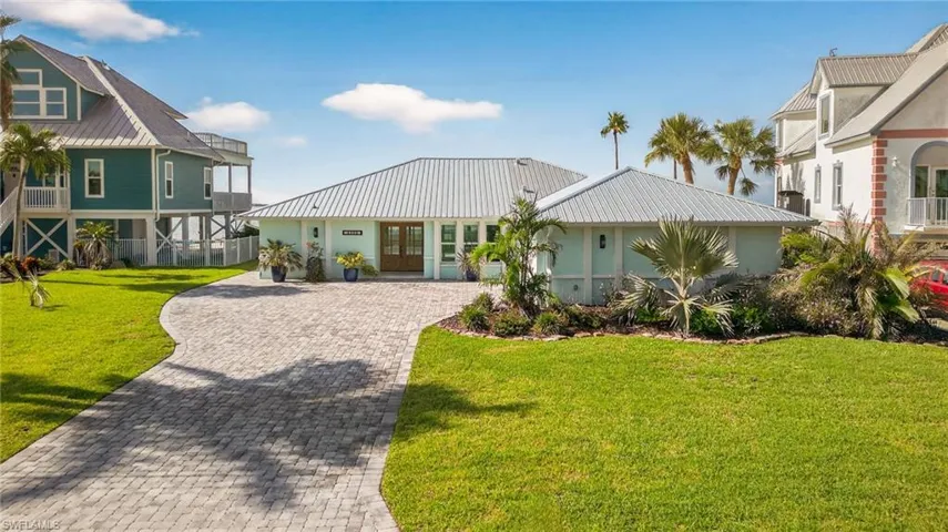 View of front of property with french doors, a metal roof, decorative driveway, a front lawn, and a standing seam roof
