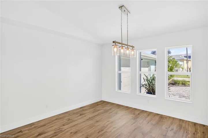 Unfurnished dining area featuring wood finished floors, a chandelier, and lofted ceiling
