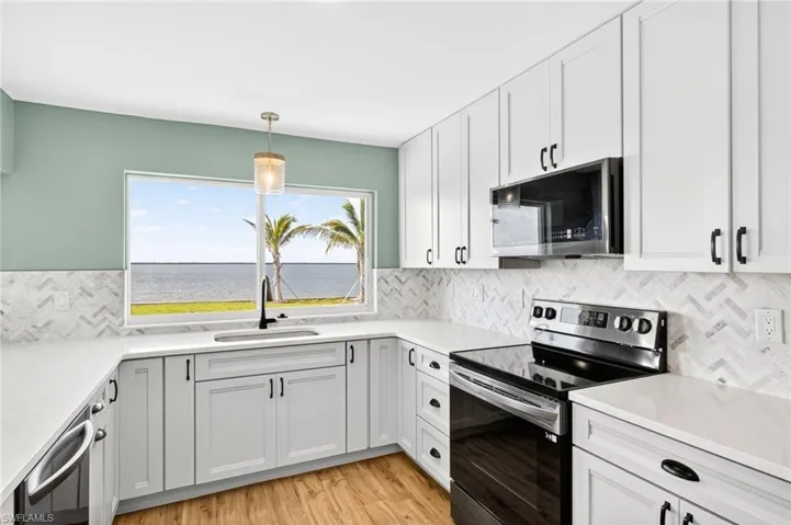 Kitchen featuring stainless steel appliances, backsplash, light wood-type flooring, and light countertops