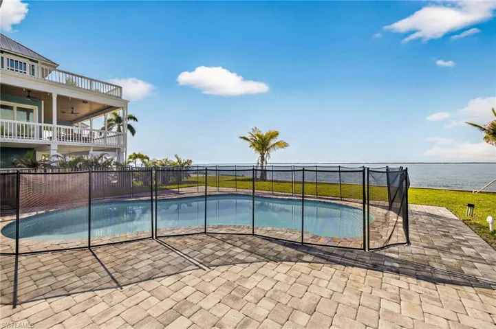 View of pool featuring a water view, a ceiling fan, and a patio