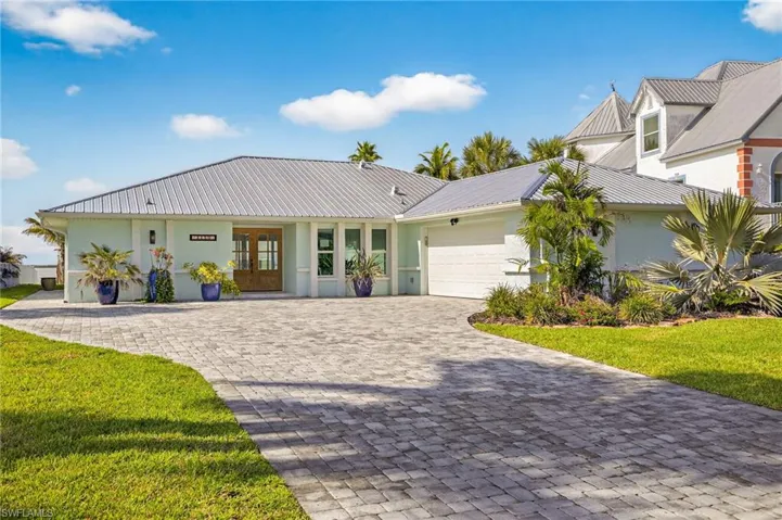 View of front facade with stucco siding, an attached garage, french doors, decorative driveway, and a front lawn