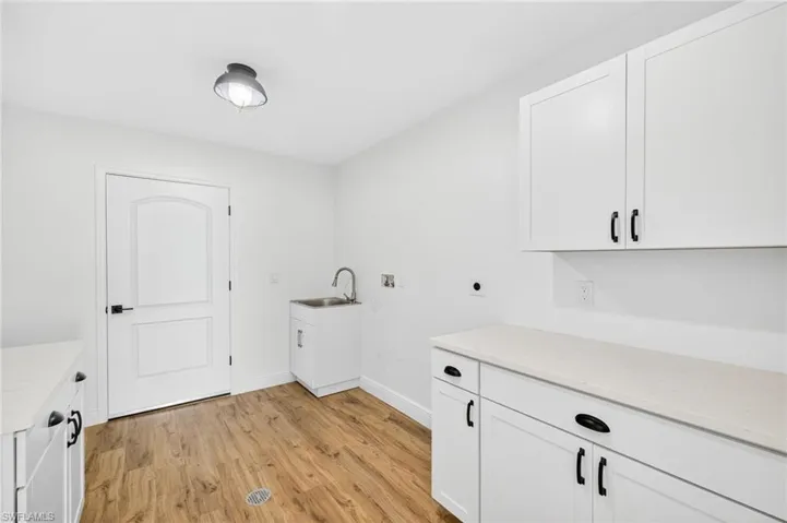Washroom featuring light wood-style floors, cabinet space, hookup for a washing machine, and electric dryer hookup