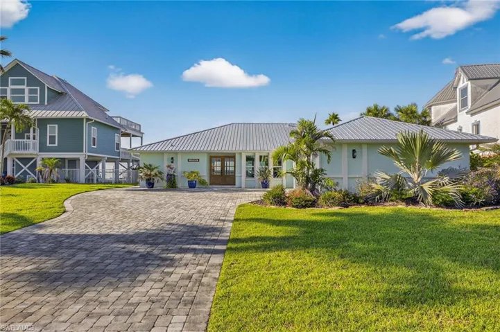View of front of property with a metal roof, a front yard, and decorative driveway