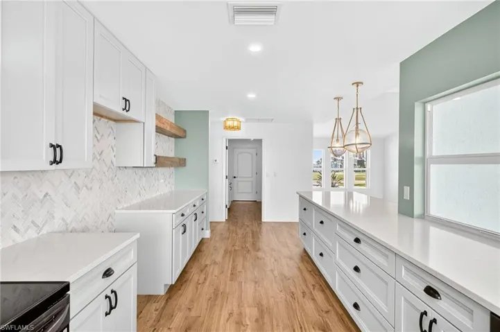 Kitchen featuring light countertops, white cabinets, light wood finished floors, hanging light fixtures, and recessed lighting