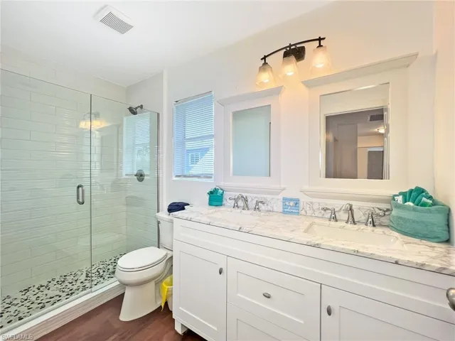 Upper Level Bathroom featuring double vanity, an enclosed shower, hardwood / wood-style flooring, everything is new