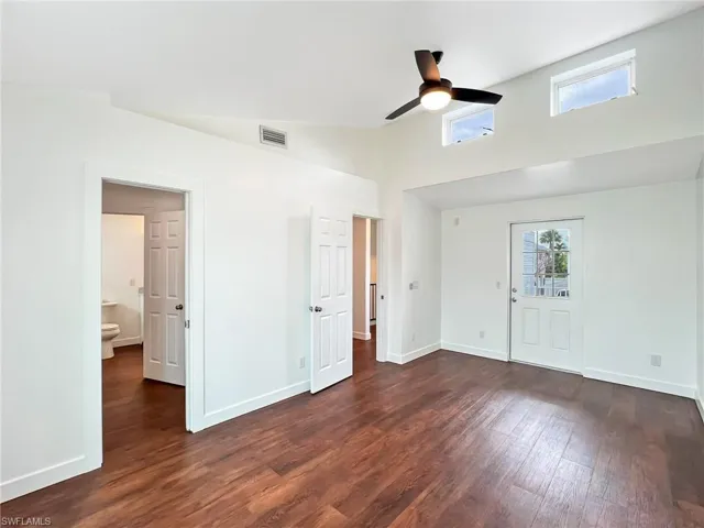 Upper level bedroom featuring ceiling fan, dark wood-style flooring, lofted ceiling, and a walk through closet and shared bathroom. Door to Open Balcony