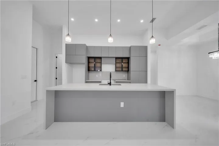 Kitchen featuring gray cabinets, modern cabinets, decorative light fixtures, and a large island