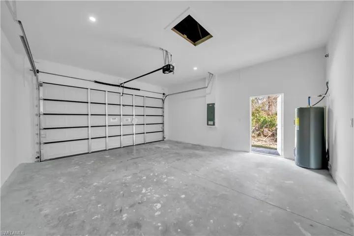 Garage featuring water heater, recessed lighting, and electric panel