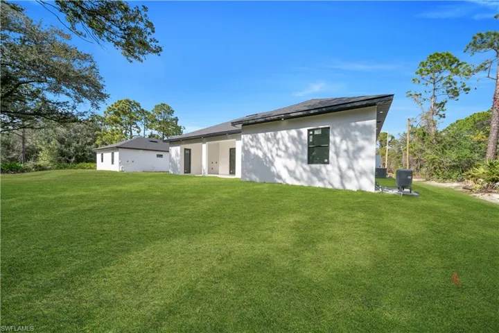 Rear view of house with a patio area, a lawn, and stucco siding