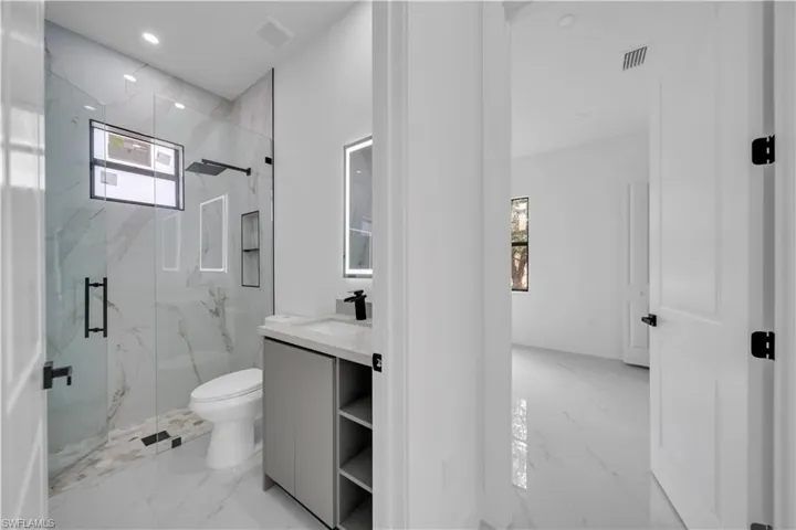 Full bath with light marble finish floors, vanity, a marble finish shower, and recessed lighting