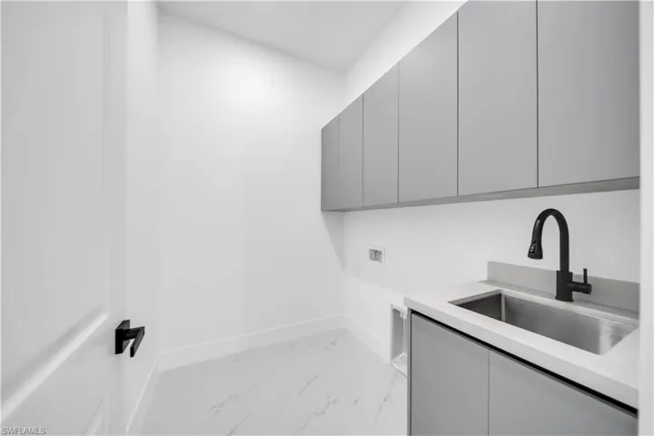 Laundry area with light marble finish flooring, cabinet space, and washer hookup