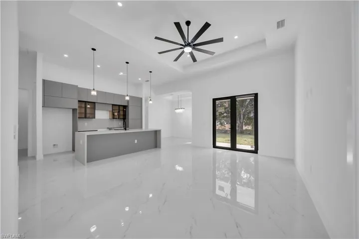 Unfurnished living room featuring light marble finish floors, recessed lighting, a raised ceiling, and a ceiling fan