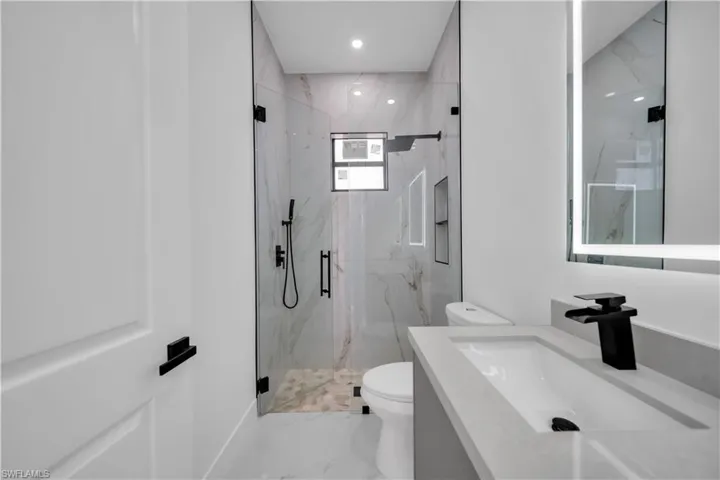 Bathroom featuring vanity, a marble finish shower, and recessed lighting