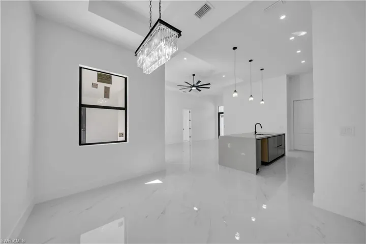 Kitchen with light stone counters, a ceiling fan, open floor plan, modern cabinets, and light marble finish floors