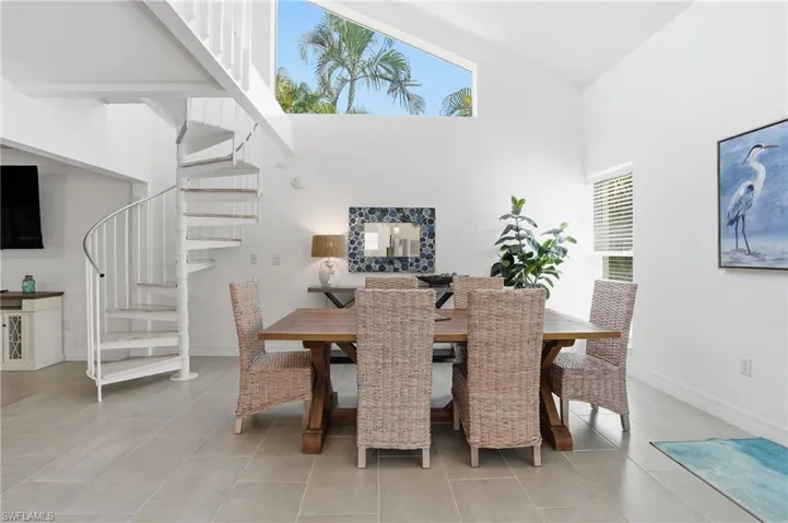 Dining area with spiral stairs & a towering ceiling- Virtually Edited Image