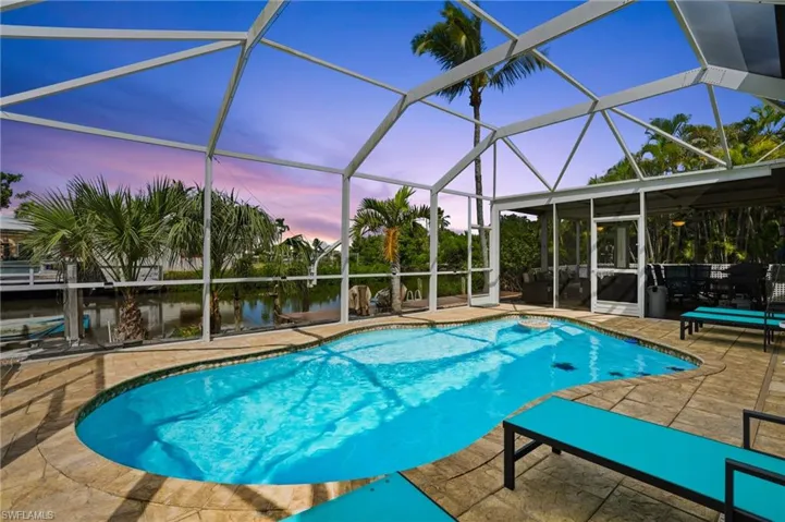 Swimming pool featuring a screened  lanai and a canal view- Virtually Edited Image