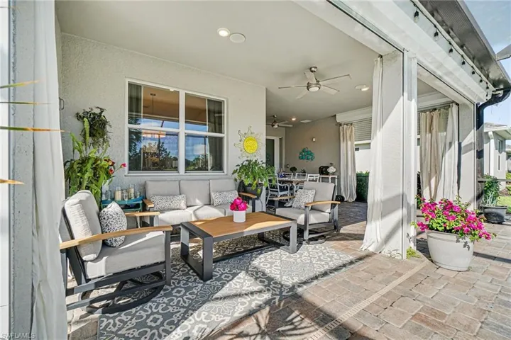 Expansive covered patio featuring brick paver flooring, multiple ceiling fans, recessed lighting, and large windows