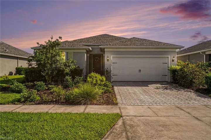 One-story residence featuring a gray exterior, a two-car garage with carriage-style hardware, and a paver driveway