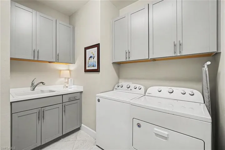 Laundry room with ample grey cabinetry, a built-in sink, and under-cabinet lighting