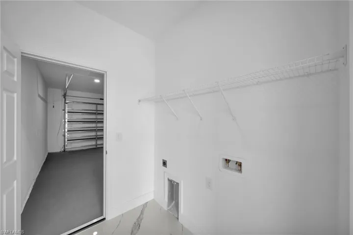 Washroom with hookup for a washing machine, electric dryer hookup, and marble finish floors